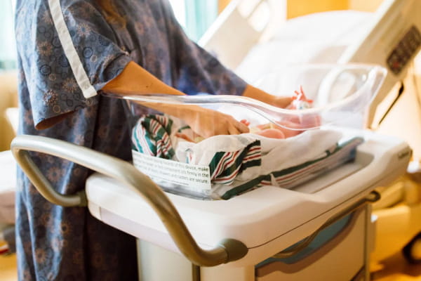 New mom caring for baby in maternity unit bassinet
