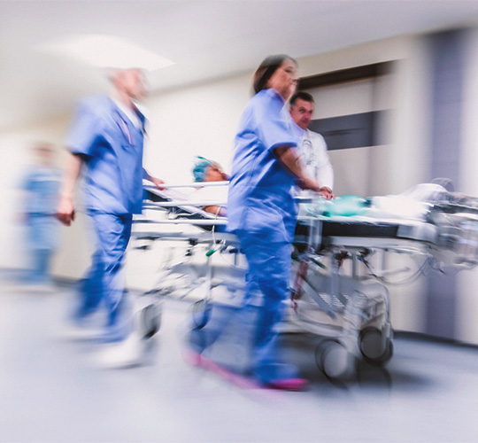 Hospital clinicians rushing patient through hallway
