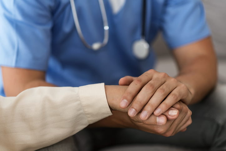 Nurse holding patient's hands close up.
